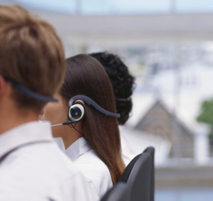 side profile of three business executives wearing headsets in an office