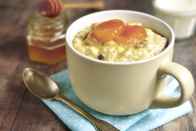 Oat porridge with honey raisins and dried apricots on rustic background.Tinted photo.